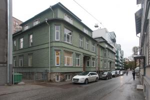 a green building with cars parked on a street at Flatmanagement Kaupmehe Apartments in Tallinn