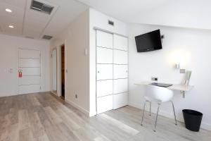 a white room with a desk and a tv on the wall at Hotel Santa Rosa, Blue Hoteles in Gijón