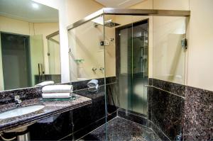 a bathroom with a sink and a glass shower at Toulouse Motel (Adult Only) in Natal