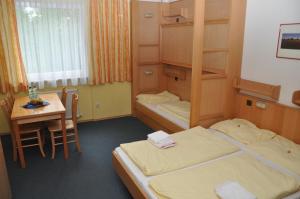 a room with two beds and a table and a desk at Eduard-Heinrich-Haus, Hostel in Salzburg