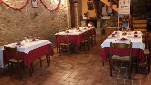 a row of tables in a room with red and white table cloth at La via del parco in Arsita