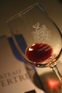 a glass of red wine sitting on a table at Château du Tertre in Arsac