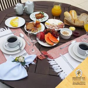 a table with plates of food and cups of coffee at Pousada Rancho da Ferradura in Petrópolis