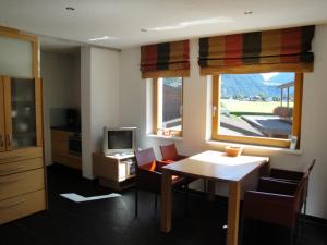 een woonkamer met een tafel en stoelen en een televisie bij Ferienwohnungen Vier Jahreszeiten in Längenfeld