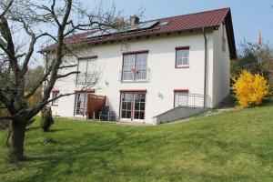 une maison blanche avec des fenêtres rouges sur une colline dans l'établissement Am Jakobusweg App3, à Bamberg