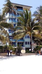 a large building with palm trees in front of it at Sunny Beachfront Studio in Mombasa