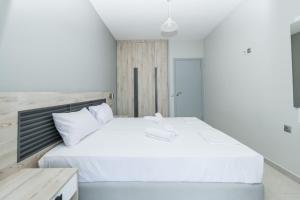 een slaapkamer met een groot wit bed met een houten hoofdeinde bij Maritina Apartments in Ixia +52 foto's