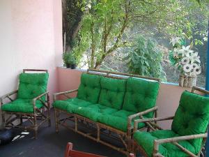two chairs and a green couch on a porch at Pousada Apice in São Luiz do Paraitinga