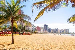 a beach with palm trees and buildings in the background at Apartamento Praia da Costa in Vila Velha