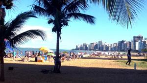 een groep mensen op een strand met een palmboom bij Apartamento Praia da Costa in Vila Velha