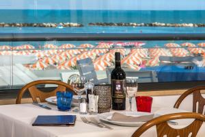 ベッラーリア・イジェア・マリーナにあるHotel Igea Spiaggiaのワイン1本とグラスをテーブルに用意しています。
