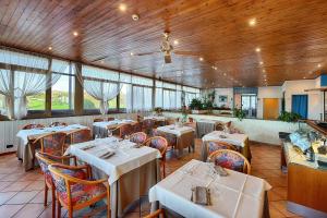 a restaurant with white tables and chairs and windows at Hotel Castello in Sovicille