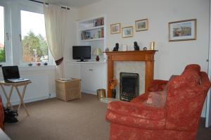 sala de estar con silla roja y chimenea en Haig Apartments, en Kirkcaldy
