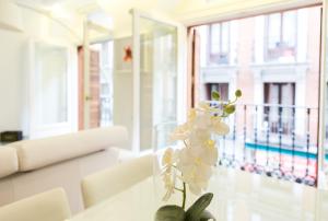un jarrón con flores blancas sobre una mesa en una habitación en Atocha Peatonal - Barrio de las letras, en Madrid