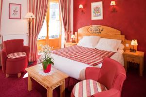 a bedroom with a bed and two chairs and a table at Hôtel Le Bois Joli in Cauterets