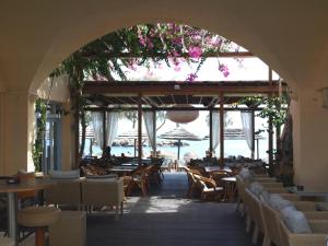un ristorante vuoto con tavoli, sedie e fiori di Levante Beach Hotel a Kamari