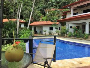 uma mesa e uma cadeira ao lado de uma piscina em Casa del Toucan em Dominical