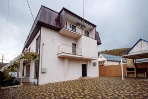 una casa bianca con balcone su un vialetto in mattoni di Country House Albatros a Praskoveyevka