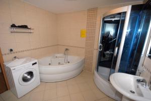 a bathroom with a tub and a washing machine at Franstal Apartments in Belgrade