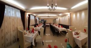 a restaurant with white tables and chairs and a chandelier at Vila Il Castello in Constanţa