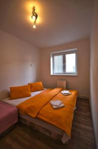 イェセニークにあるApartman Nad Laznemiのベッドルーム1室(大型ベッド1台、オレンジのシーツ、窓付)