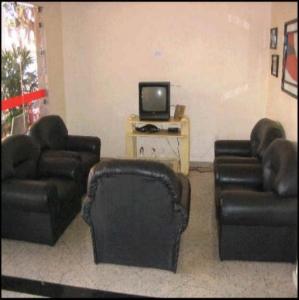 a living room with two leather couches and a tv at Hotel Topazio Ltda in Umuarama