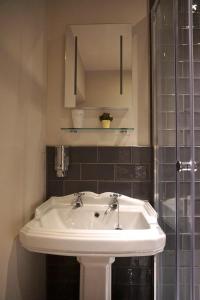 a white sink in a bathroom with a shower at The Game Cock Inn in Austwick