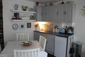 cocina con armarios blancos, mesa y sillas en Cara-Na-Mara, en Killough