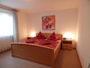 a bedroom with a large bed with red pillows at Ferienwohnung Vogl in Drachselsried