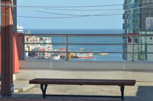 a bench sitting on a balcony looking out at the ocean at Busan Popcorn Hostel in Busan