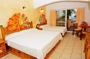 a hotel room with two beds and a dining room at Hotel Casa Sun and Moon in Zihuatanejo