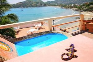 a balcony with a swimming pool and a beach at Hotel Casa Sun and Moon in Zihuatanejo