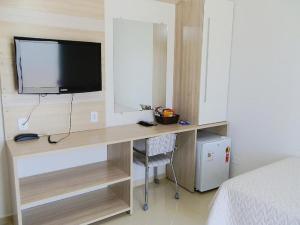 a bedroom with a desk with a tv and a bed at Lisboa Palace Hotel in Alta Floresta