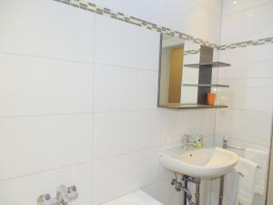 Un baño blanco con lavabo y espejo. en AVI City Apartments GoodHouse, en Düsseldorf 31 fotos más