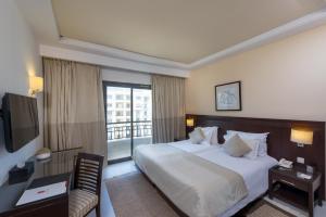 a hotel room with a bed and a balcony at Le Corail Suites Hotel in Tunis