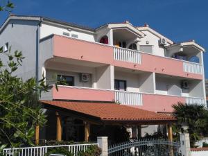 a large white and pink building with a red roof at Ivano Apartments in Grebaštica