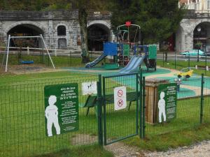 a park with a playground with signs on a fence at Beau Soleil in Eaux-Bonnes