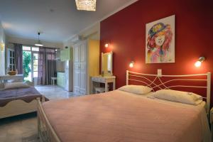 a bedroom with a large bed and a red wall at Valentino Corfu in Ýpsos