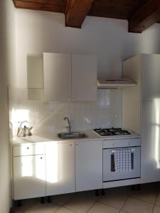 a white kitchen with a sink and a stove at Casa Vacanza Isola in Orta San Giulio +15 photos