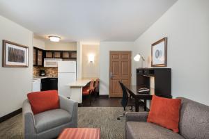 a living room with a couch and a table and a kitchen at Staybridge Suites Chantilly Dulles Airport, an IHG Hotel in Chantilly