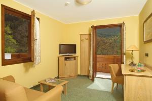 ein Wohnzimmer mit einem Sofa, einem TV und einem Fenster in der Unterkunft Hotel Conca Verde in Zone