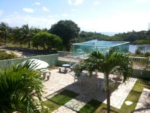 a patio with a glass house and palm trees at Pousada Lagoa Azul in Jacumã
