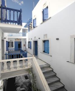 een trap in een wit gebouw met blauwe deuren en ramen bij Manto Apartments in Tinos Town