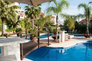 a resort pool with a wooden bridge and palm trees at Aloha Hill Club Apartment in Marbella