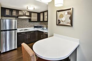 Mayfield HeightsにあるStaybridge Suites Cleveland Mayfield Heights Beachwood by IHGの白いテーブルと冷蔵庫のあるキッチン