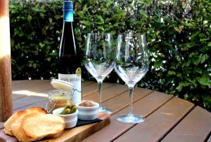 three wine glasses and bread on a wooden table at Roma On Riccarton Motel in Christchurch