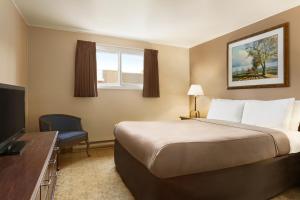 a hotel room with a bed and a television at Travelodge by Wyndham Kenora in Kenora