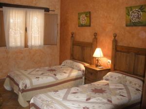 a bedroom with two beds and a lamp on a table at Complejo Peñafiel in Zarza la Mayor