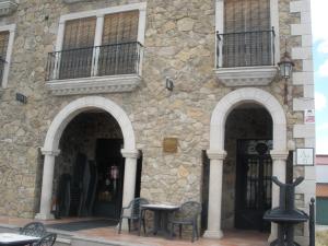 un edificio de piedra con una mesa y sillas delante de él en Complejo Peñafiel, en Zarza la Mayor