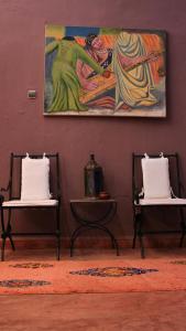 two chairs in a room with a painting on the wall at Dar Tadout in Aït Ourir